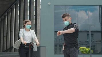 das Mädchen kommt zu das Treffen auf ein elektrisch Roller. jung Menschen im medizinisch Masken auf ihr Gesichter. Treffen von zwei jung glücklich Menschen auf das Straße im das Mitte von das Stadt. video