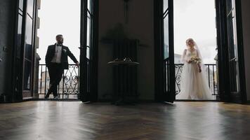 The wedding morning of the bride and groom in the hotel. The bride and groom stand on different balconies and look at each other. Views of the bride and groom in the distance. video