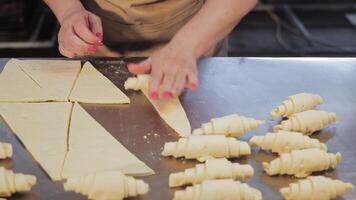The baker forms croissants from the dough. Confectionery made from dough. Twisting the dough for Croissant production video