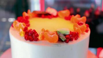 A cake with mandarin oranges and a pomegranate in a shop window. video