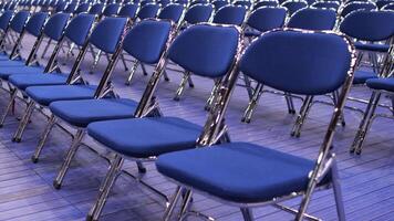 rows of empty blue chairs without spectators before seminar, concert, primaries video