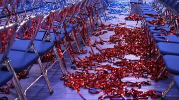 red and blue Confetti and tinsel on the floor. rows of empty blue chairs video