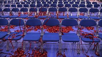 rows of empty blue chairs. red Confetti and tinsel on the floor video