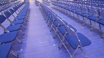 rows of empty blue chairs without spectators before seminar, concert, primaries video