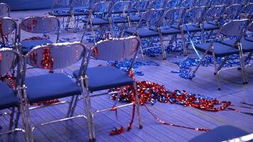 rows of empty blue chairs. red Confetti and tinsel on the floor video