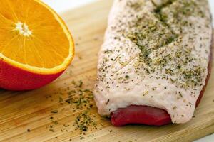 duck fillet with seasonings and orange on a wooden cutting board photo