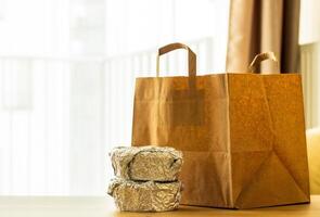 package of food from delivery stands on the table, containers with hot food packed in foil and sushi, food delivery concept photo