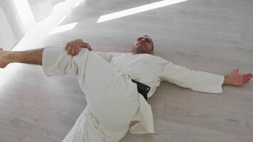 Hommes mensonge sur le sol faire chaud en haut jambe des exercices pour karaté session video