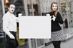 Your text here. Actors mimes holding empty white letter. Colorful portrait with gray background. April fools day photo
