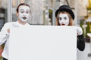 Your text here. Actors mimes holding empty white letter. Colorful portrait with gray background. April fools day photo