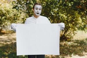 Your text here. Actors mimes holding empty white letter. Colorful portrait with green background. April fools day photo