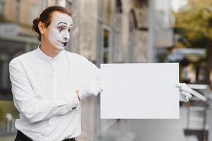 Your text here. Actor mime holding empty white letter. Colorful portrait with gray background. April fools day photo