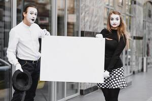Your text here. Actors mimes holding empty white letter. Colorful portrait with gray background. April fools day photo