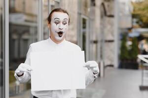 Your text here. Actor mime holding empty white letter. Colorful portrait with gray background. April fools day photo