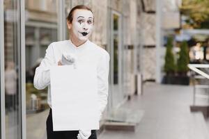 Your text here. Actor mime holding empty white letter. Colorful portrait with gray background. April fools day photo