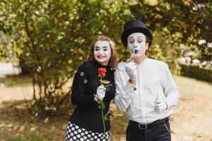 Mime artist blowing a bubble through wand on green background photo