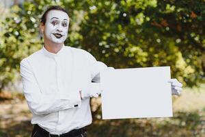 Your text here. Actors mimes holding empty white letter. Colorful portrait with green background. April fools day photo