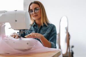 Attractive female fashion designer is working in her workshop. Stylish woman in process of creating new clothes collection. photo
