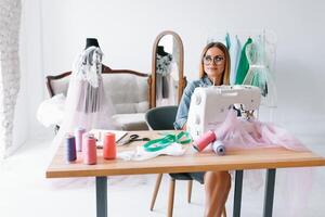 Attractive female fashion designer is working in her workshop. Stylish woman in process of creating new clothes collection. photo