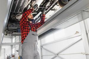 Mechanic working under car at the repair garage. Auto mechanic working in garage. Repair service. photo