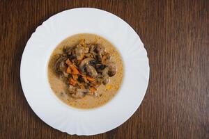 Plate with delicious mushrooms with creamy sauce on wooden background photo