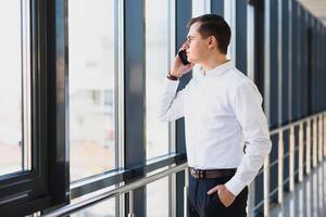 Business man in suit talking on phone and looking away near the window. photo