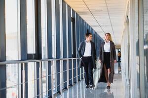 Business men and women shaking hands with a smile on the background of the large panoramic windows in a modern business center. Models dressed in a dark business suits. photo