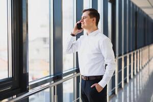 Business man in suit talking on phone and looking away near the window. photo
