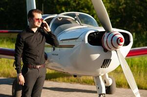 Business man with his airplanes. He is walking in the airport with the smart phone and making a call. photo