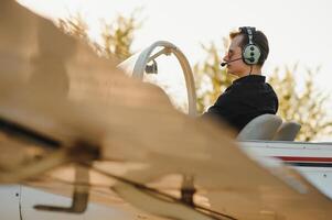 Smiling attractive young man pilot sitting in cabin of small aircraft photo
