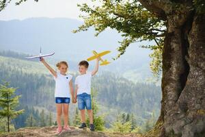 Children pilot aviator with airplane dreams of traveling in summer in nature. Vacation concept. photo