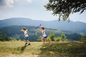 Boy and girl playing with toy airplanes on a background of mountains. Happy childhood and vacation in the mountains. photo