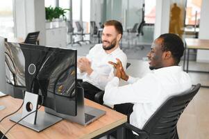 Two successful trader sitting in office, checking cryptocurrency information data on finance market graph, pointing on monitor photo