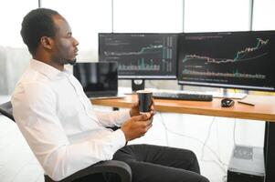 African American trader works at computer with displayed real-time stocks photo