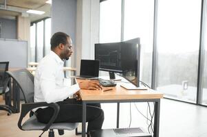 African American trader works at computer with displayed real-time stocks photo
