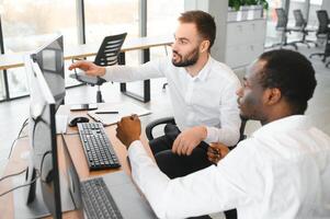 Two successful trader sitting in office, checking cryptocurrency information data on finance market graph, pointing on monitor photo