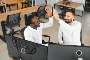 Two successful trader sitting in office, checking cryptocurrency information data on finance market graph, pointing on monitor photo
