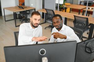 Two successful trader sitting in office, checking cryptocurrency information data on finance market graph, pointing on monitor photo