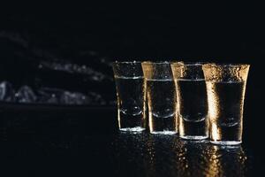 Vodka in shot glasses on dark background photo
