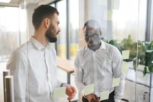colleagues discuss and stick notes on the glass photo