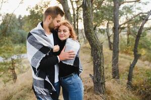 young romantic couple in love in a gentle hug and warm themselves with a plaid, the concept of romantic love relationships. photo