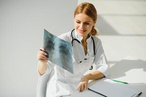 Female doctor working at office desk and smiling, office interior on background. photo