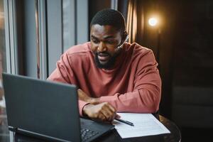 Afro american talks chat on computer sits in cafe with cup of coffee. Black man calls on laptop on link and speaks. He wears in shirt and suit jacket. link online connection photo