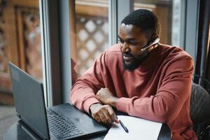 Afro american talks chat on computer sits in cafe with cup of coffee. Black man calls on laptop on link and speaks. He wears in shirt and suit jacket. link online connection photo