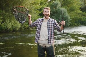 Fisherman hunting trouts in mountain river. Fishing net detail. photo