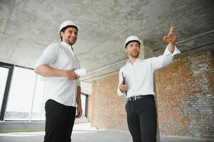 Two civil engineers or architects man inspecting construction of house. photo