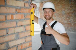 Man builder working in construction site. Male repairer in overall and helmet. photo