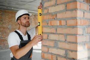 Man builder working in construction site. Male repairer in overall and helmet. photo