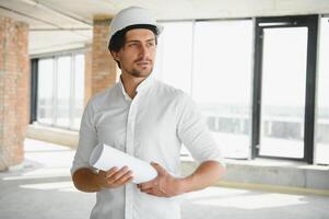 Portrait of an architect builder studying layout plan of the rooms, serious civil engineer working with documents on construction site, building and home renovation, professional foreman at work. photo