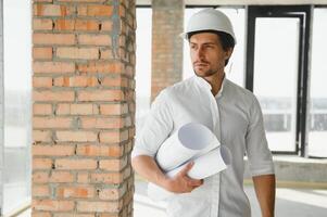 Portrait of man architect at building site. Confident construction manager wearing hardhat. Successful mature civil engineer at construction site with copy space. photo